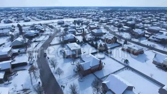 沿着郊区的街道飞过白雪覆盖的住宅和庭院视频的预览图