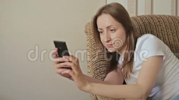 年轻漂亮的女人在家里用智能手机视频的预览图