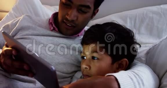父子俩在床上用数码平板电脑视频的预览图