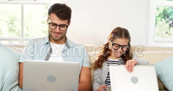 父亲和女儿在客厅里用笔记本电脑视频的预览图