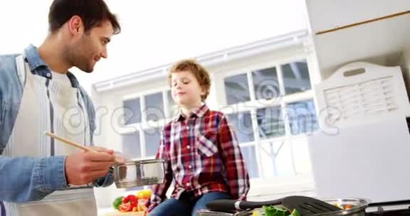 男孩看着父亲做饭视频的预览图