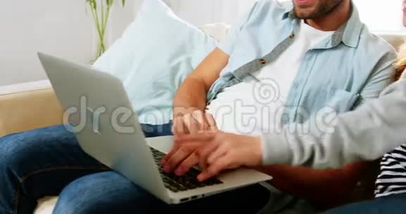 父亲和女儿在客厅用笔记本电脑视频的预览图