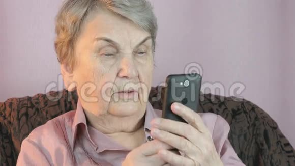 老妇人拿着手机在室内视频的预览图