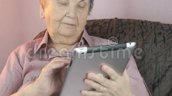 手持银制平板电脑的老妇人视频的预览图