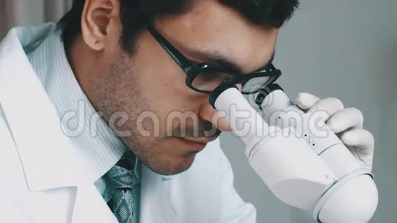 年轻的科学家透过显微镜看视频的预览图