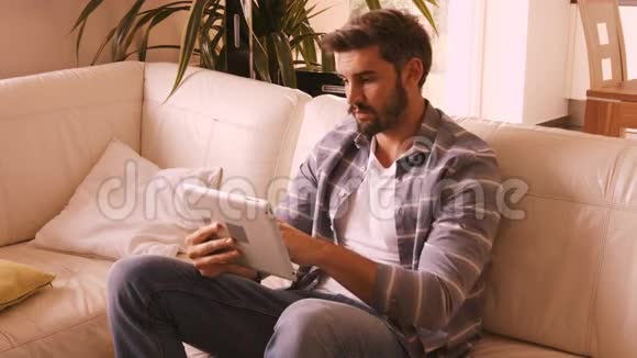 男人在沙发上放松使用数字平板电脑视频的预览图