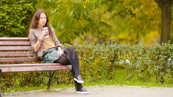 秋天的概念美丽的女人在秋天的公园里喝咖啡视频的预览图