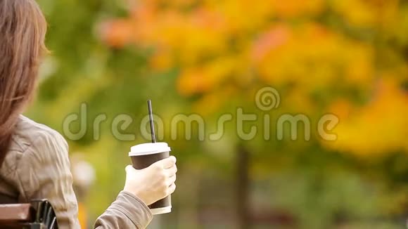 秋天的概念美丽的女人在秋天的公园里喝咖啡视频的预览图
