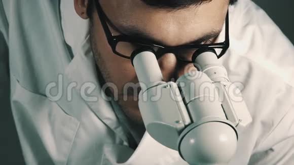 年轻的科学家透过显微镜看视频的预览图