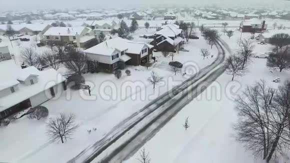 沿着郊区的街道飞过白雪覆盖的住宅和庭院视频的预览图