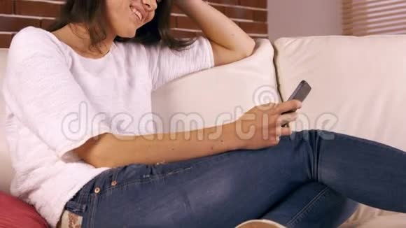 微笑的女人在沙发上发短信视频的预览图