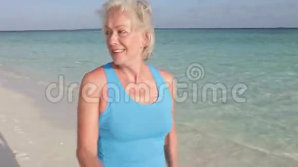 在美丽的海滩上散步的老年妇女视频的预览图
