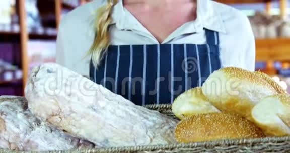 微笑着在面包柜台拿着一篮子面包的女员工视频的预览图