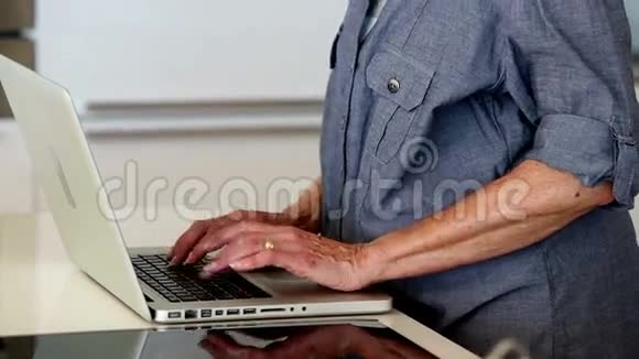 在柜台上用笔记本电脑的老妇人视频的预览图