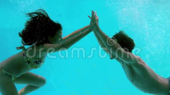 快乐的一对情侣在游泳池的水下牵手视频的预览图