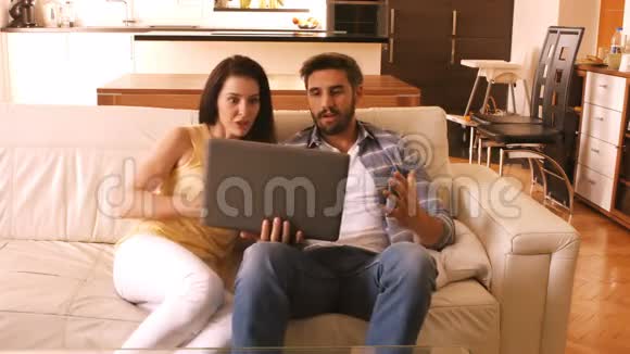 情侣在沙发上放松使用笔记本电脑视频的预览图