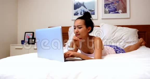 美丽的女人在床上放松使用笔记本电脑视频的预览图