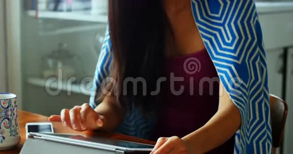 美丽的女人一边喝咖啡一边用数码平板电脑视频的预览图
