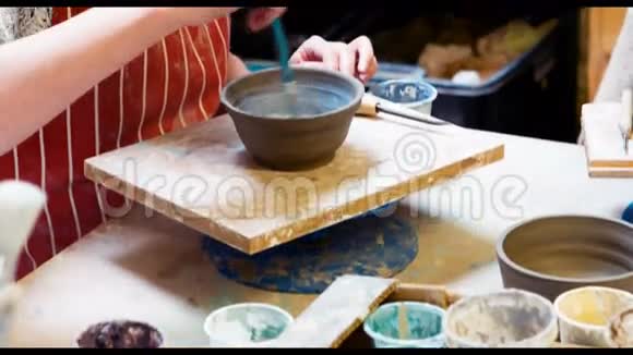 女艺术家在陶器碗上作画视频的预览图