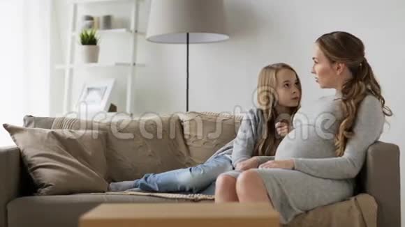 快乐的孕妇和坐在沙发上的女孩视频的预览图