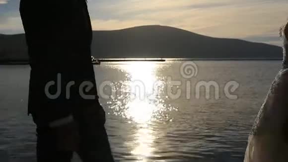日落时分一对新婚夫妇在海上的剪影婚礼在视频的预览图
