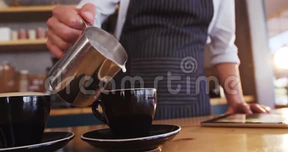 服务员在准备咖啡时往咖啡杯里倒牛奶视频的预览图