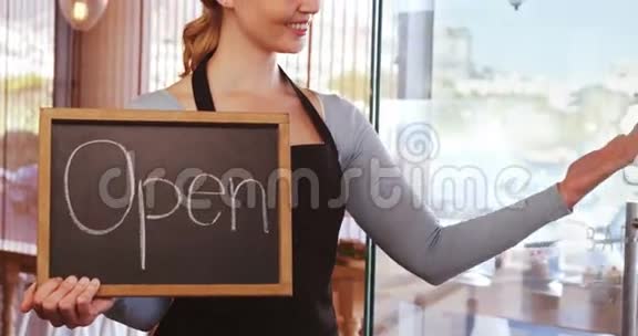 微笑的女服务生展示石板和开放的标志视频的预览图