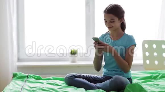 微笑的女孩在家里用智能手机发短信视频的预览图