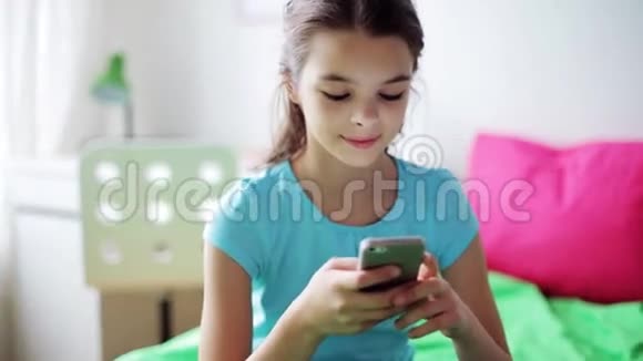 微笑的女孩在家里用智能手机发短信视频的预览图