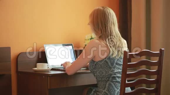 漂亮的女人坐在房子里的桌子上用笔记本电脑工作视频的预览图