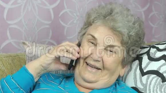 这位老妇人在家里用手机说话视频的预览图