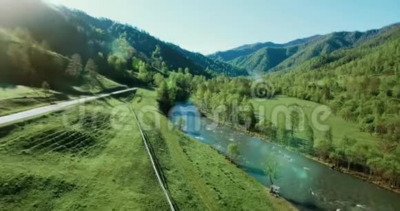 在阳光明媚的夏日早晨空中飞过新鲜的山河和草地农村土路下面视频的预览图
