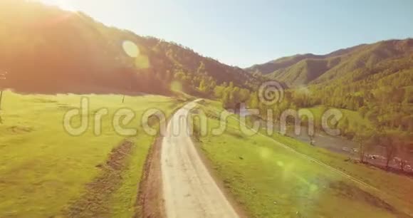 在阳光明媚的夏日早晨中气飞越新鲜的山河和草地农村土路下面视频的预览图