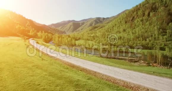 超高清4K鸟瞰图在阳光明媚的夏季早晨低飞过新鲜寒冷的山河草地和道路视频的预览图