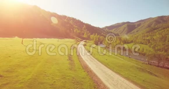 在阳光明媚的夏日早晨中气飞越新鲜的山河和草地农村土路下面视频的预览图