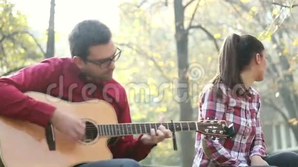 帅哥弹吉他美女坐在公园旁边视频的预览图