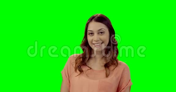 微笑着站在绿色屏幕上的美丽女人视频的预览图
