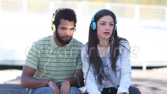 可爱的年轻夫妇带着耳机听音乐视频的预览图