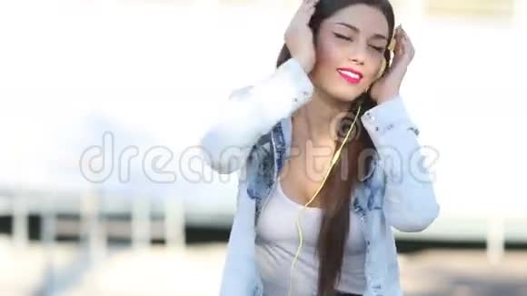 漂亮的黑发女人带着耳机听音乐视频的预览图