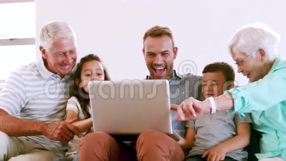可爱的家人在沙发上用笔记本电脑视频的预览图