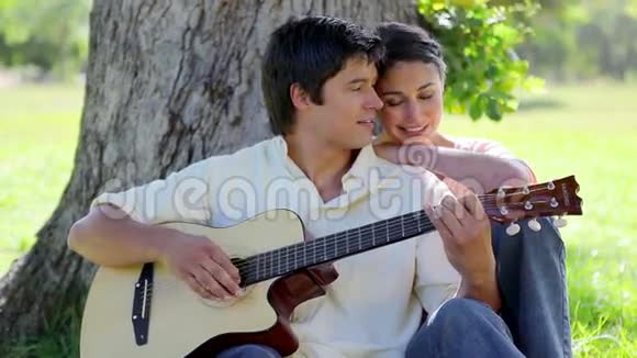 微笑的男人为他的女朋友弹吉他视频的预览图