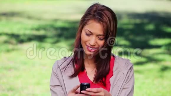 微笑的黑发女人站着用手机视频的预览图