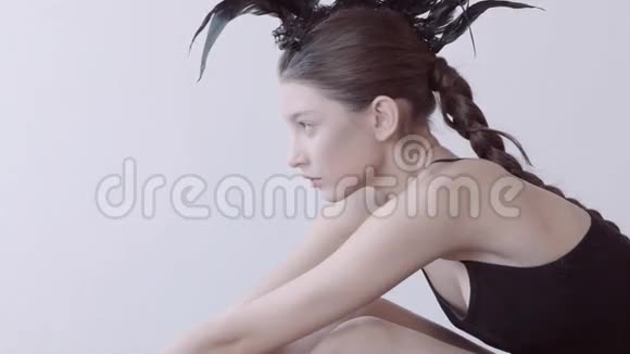 年轻的混血白种人女性时尚肖像与羽毛莫霍克配件穿黑色紧身衣视频的预览图