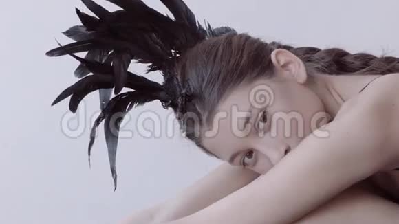 年轻的混血白种人女性时尚肖像与羽毛莫霍克配件穿黑色紧身衣视频的预览图