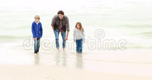 父亲和孩子们在海滩上奔跑视频的预览图