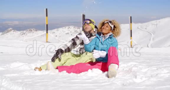 一对夫妇坐在滑雪坡上下雪视频的预览图