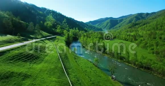 在阳光明媚的夏日早晨空中飞过新鲜的山河和草地农村土路下面视频的预览图