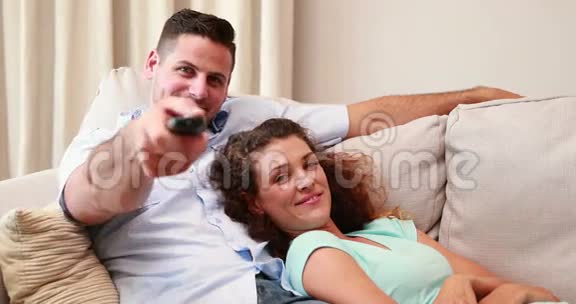 快乐的年轻夫妇在沙发上看电视视频的预览图