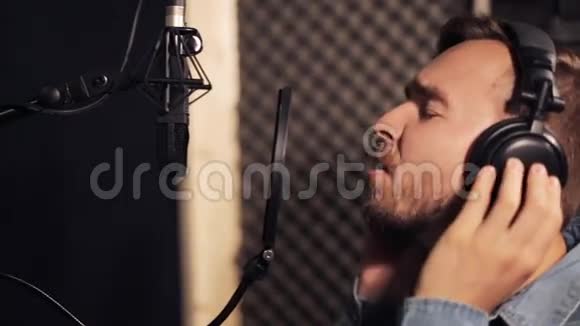 带着耳机在录音室唱歌的男人视频的预览图
