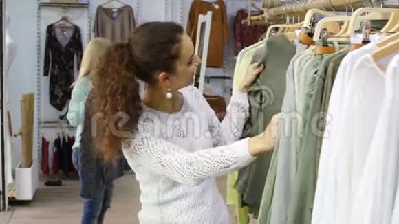 快乐的年轻女孩在商店里挑选新衣服视频的预览图
